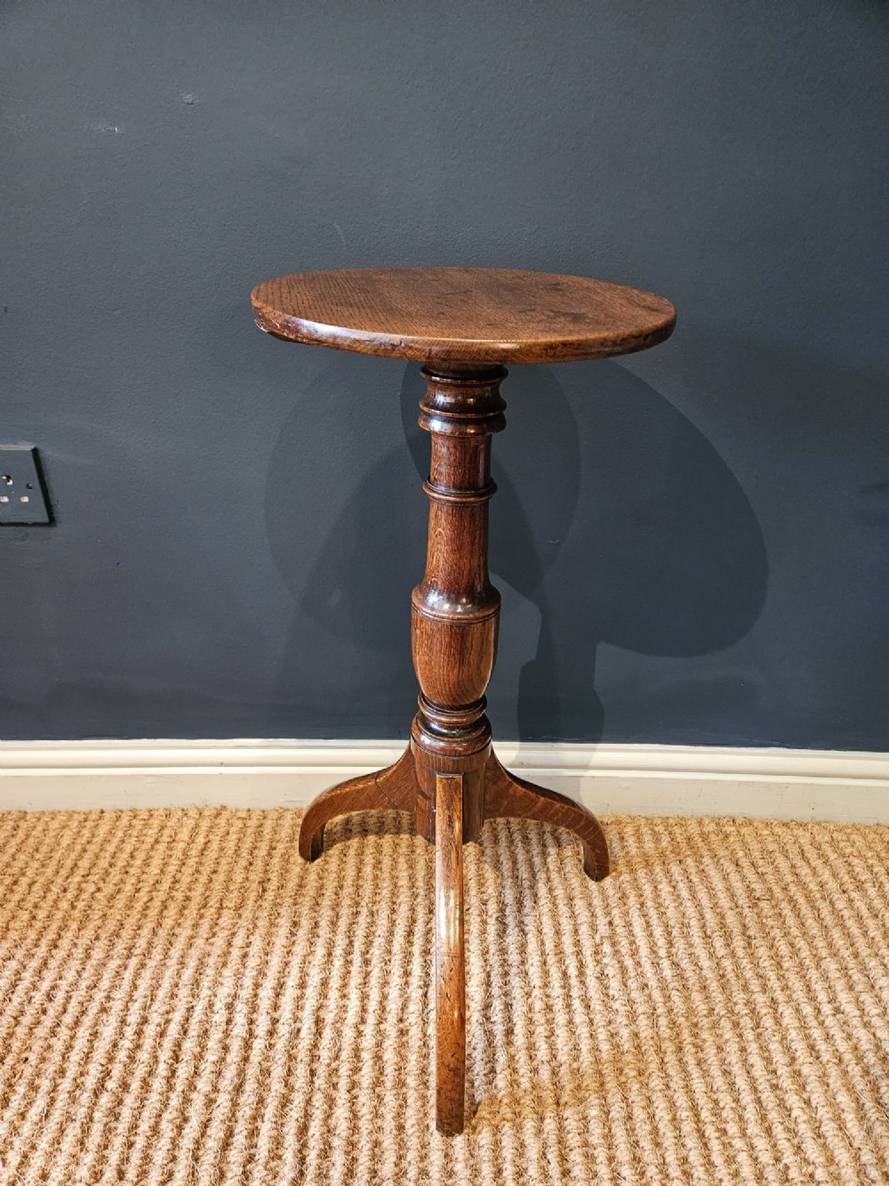 A Regency oak candle table with a circular top, a turned central pedestal stem, and three splayed tripod legs. View II