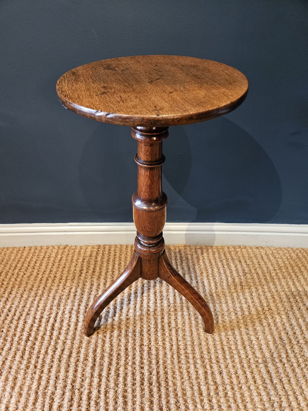 A Regency oak candle table with a circular top, a turned central pedestal stem, and three splayed tripod legs. View IV