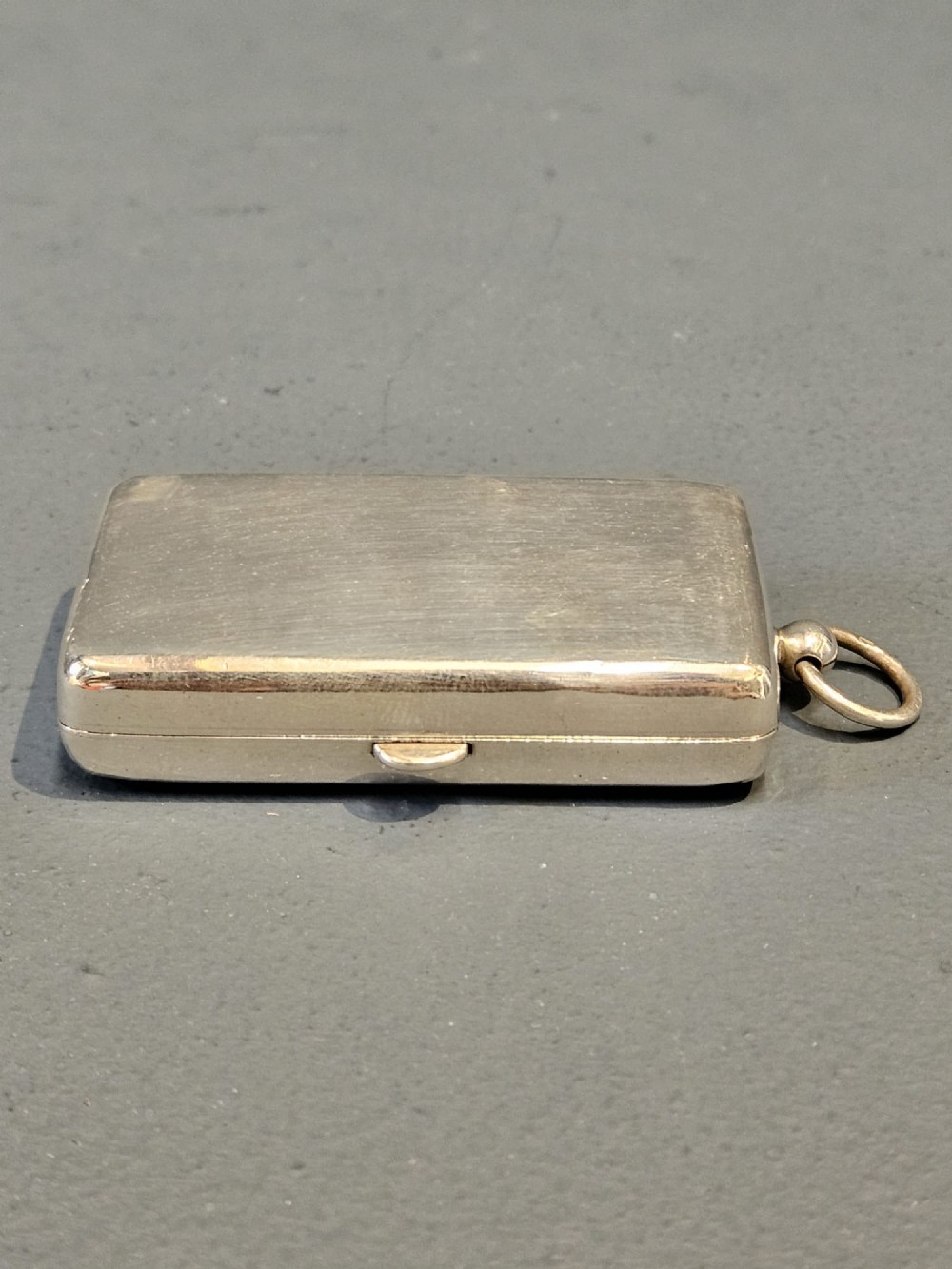 A rectangular polished sterling silver double sovereign and banknote case featuring a top suspension ring and side push-button catch. View IV