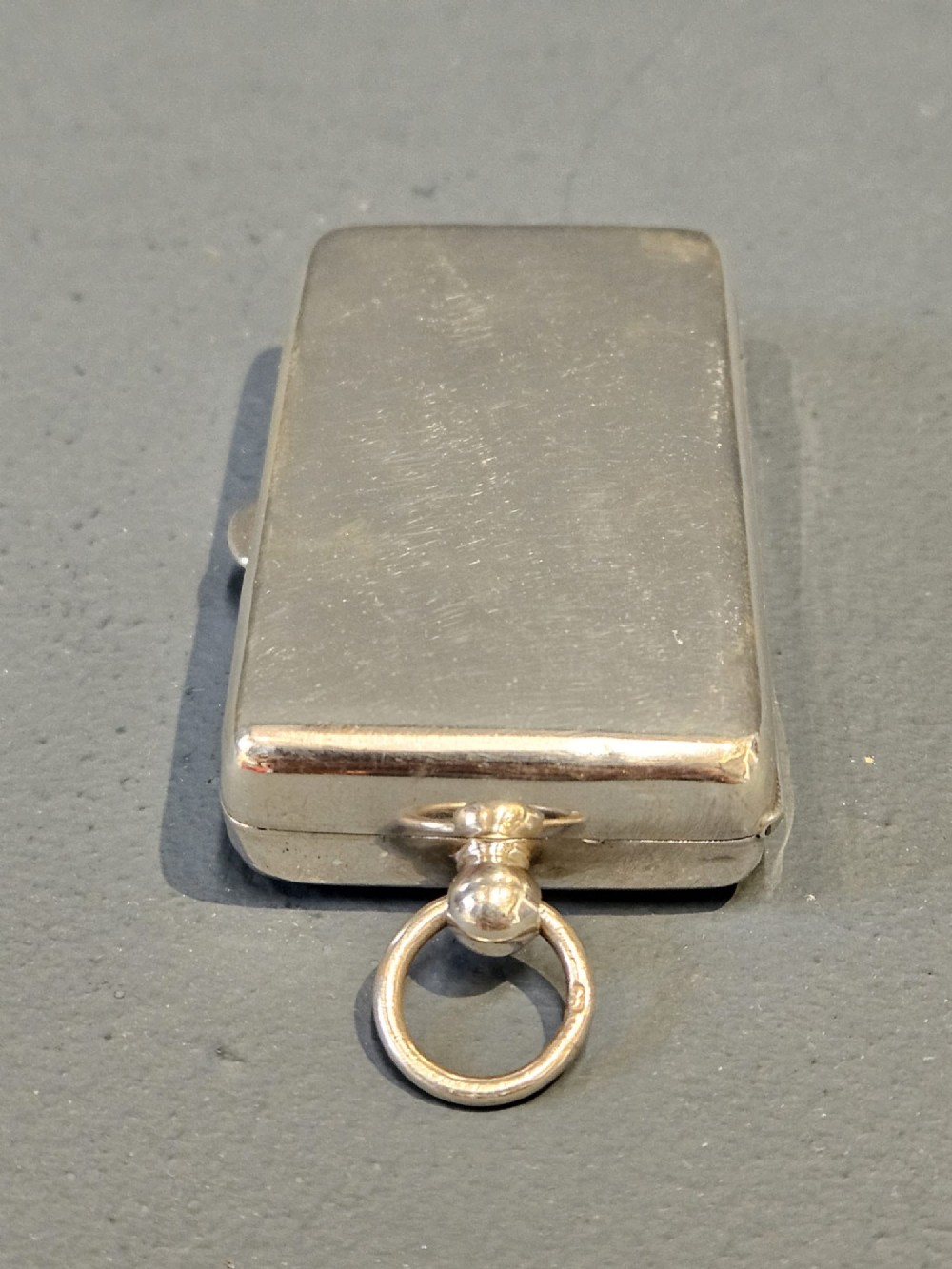 A rectangular polished sterling silver double sovereign and banknote case featuring a top suspension ring and side push-button catch. View VI