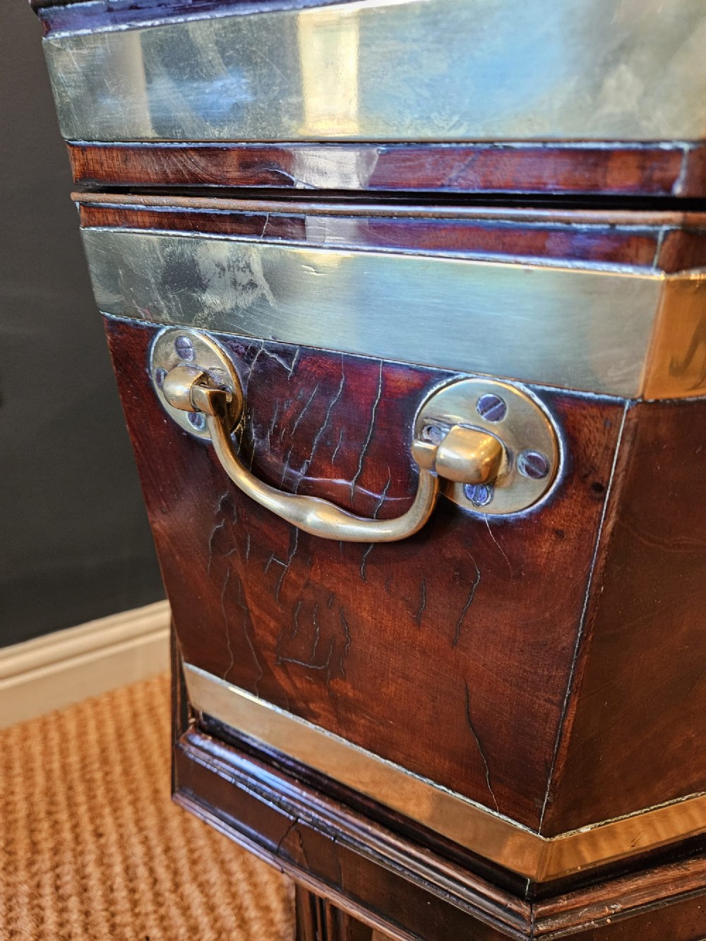An octagonal George III mahogany wine cooler featuring brass binding bands, a hinged lid with starburst marquetry, and four square tapered legs. View III