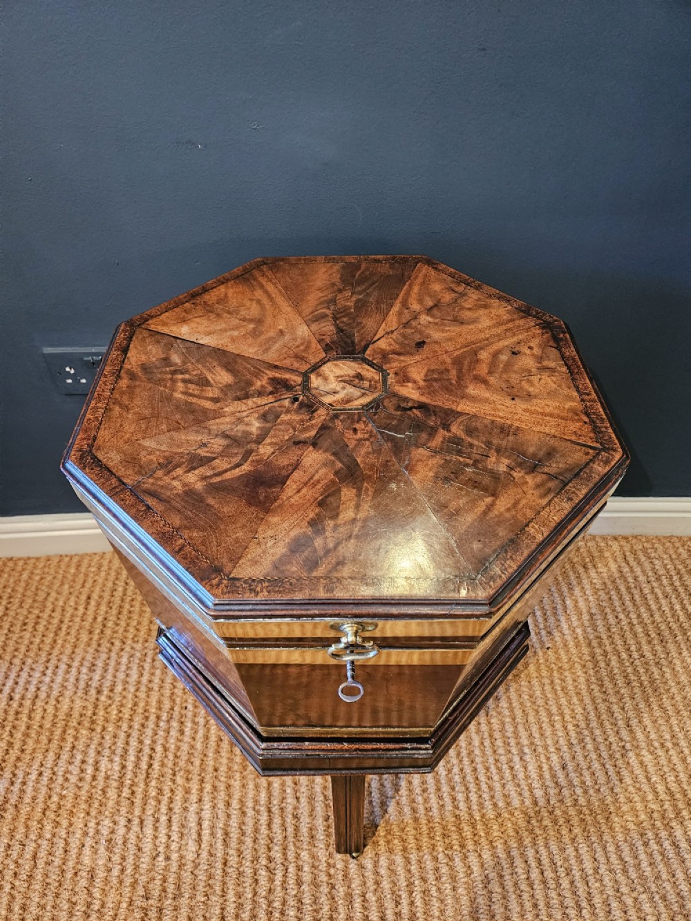 An octagonal George III mahogany wine cooler featuring brass binding bands, a hinged lid with starburst marquetry, and four square tapered legs. View IX