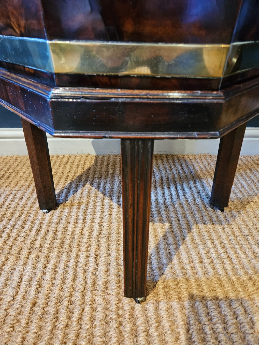 An octagonal George III mahogany wine cooler featuring brass binding bands, a hinged lid with starburst marquetry, and four square tapered legs. View X