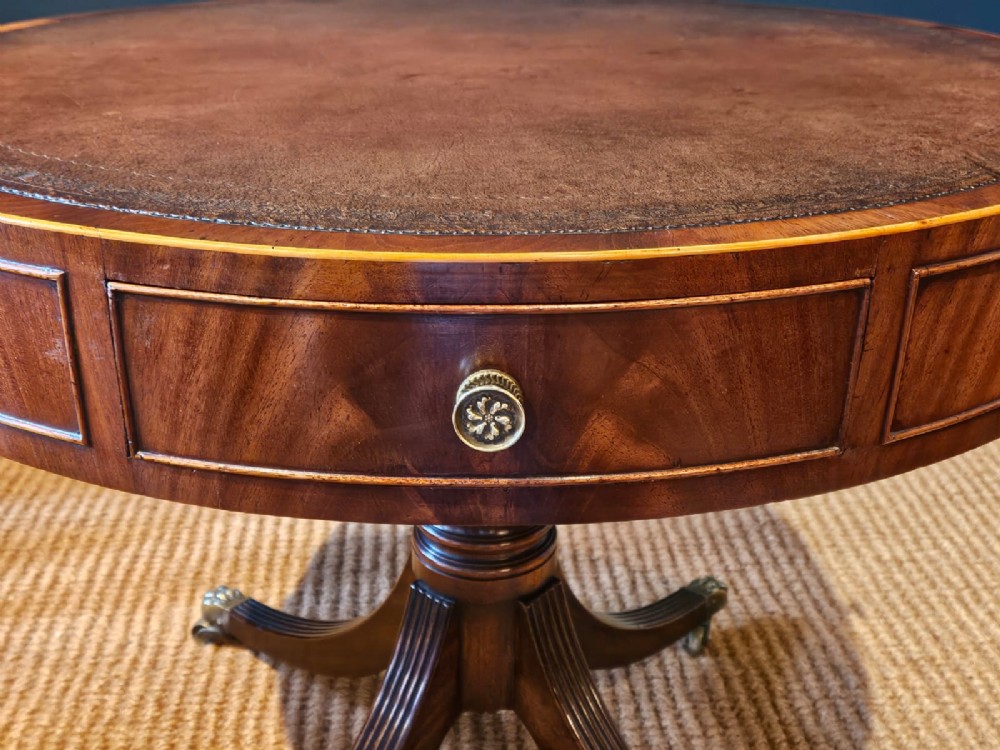 A small circular Regency mahogany drum table with a brown leather inset top, frieze drawers, turned pedestal stem, and reeded splayed legs on brass castors. View II
