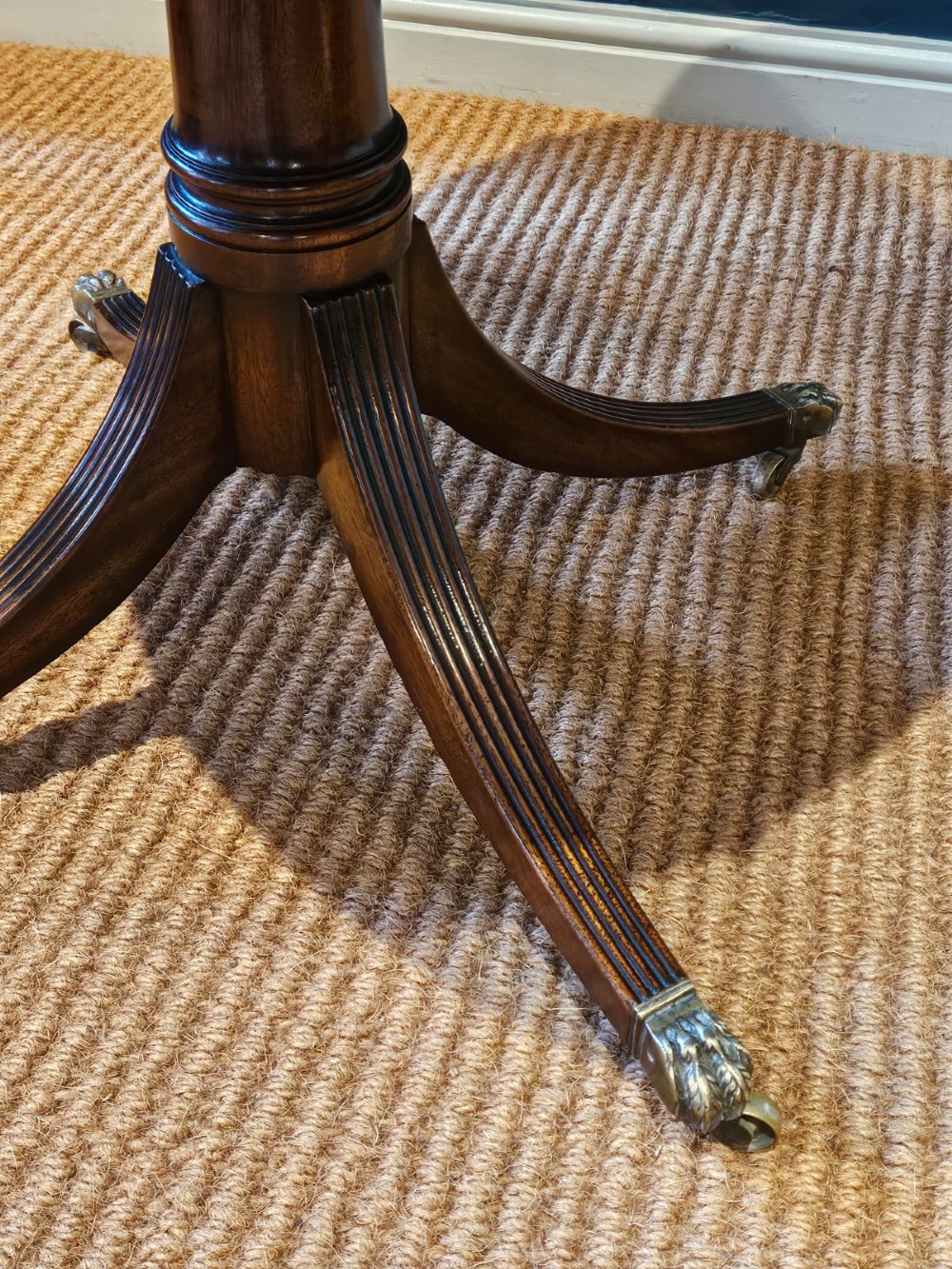 A small circular Regency mahogany drum table with a brown leather inset top, frieze drawers, turned pedestal stem, and reeded splayed legs on brass castors. View III