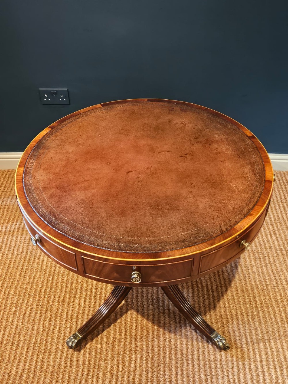 A small circular Regency mahogany drum table with a brown leather inset top, frieze drawers, turned pedestal stem, and reeded splayed legs on brass castors. View IV