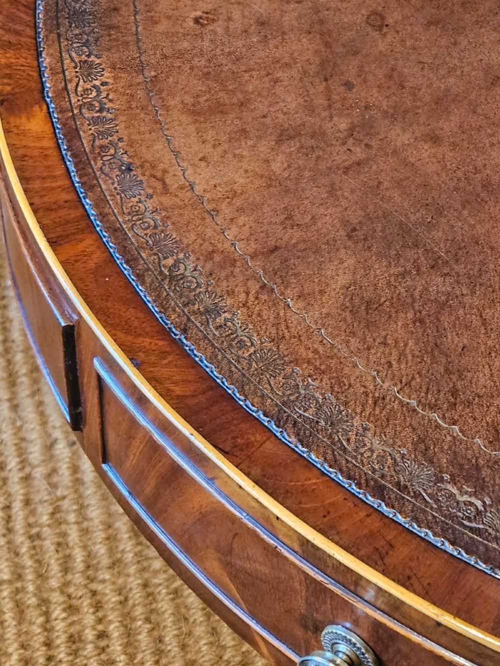 A small circular Regency mahogany drum table with a brown leather inset top, frieze drawers, turned pedestal stem, and reeded splayed legs on brass castors. View V