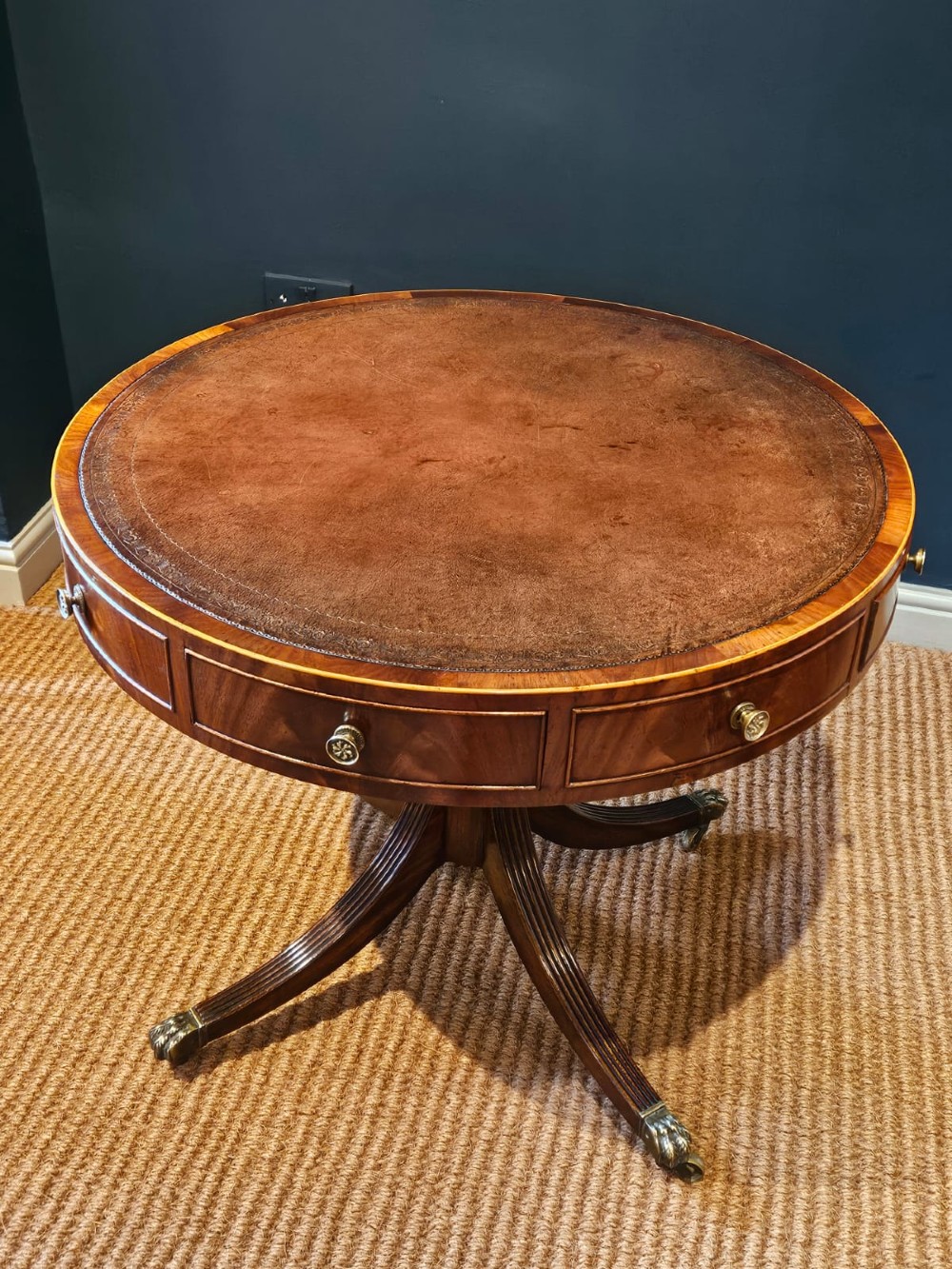 A small circular Regency mahogany drum table with a brown leather inset top, frieze drawers, turned pedestal stem, and reeded splayed legs on brass castors. View VI