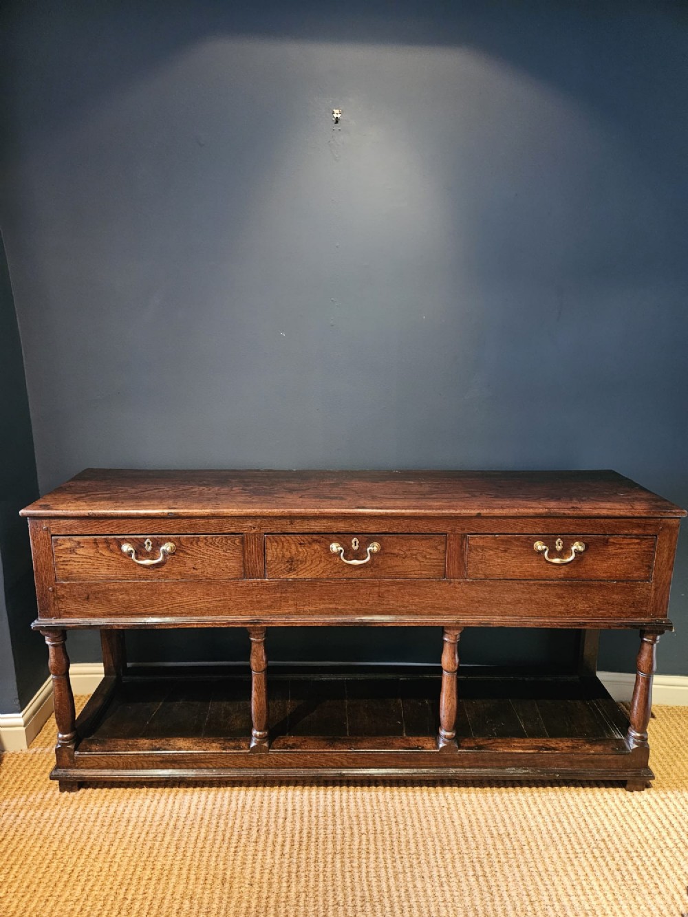 An 18th-century George II oak pot board dresser featuring three frieze drawers with brass handles set above an open lower shelf and turned baluster supports. View VIII