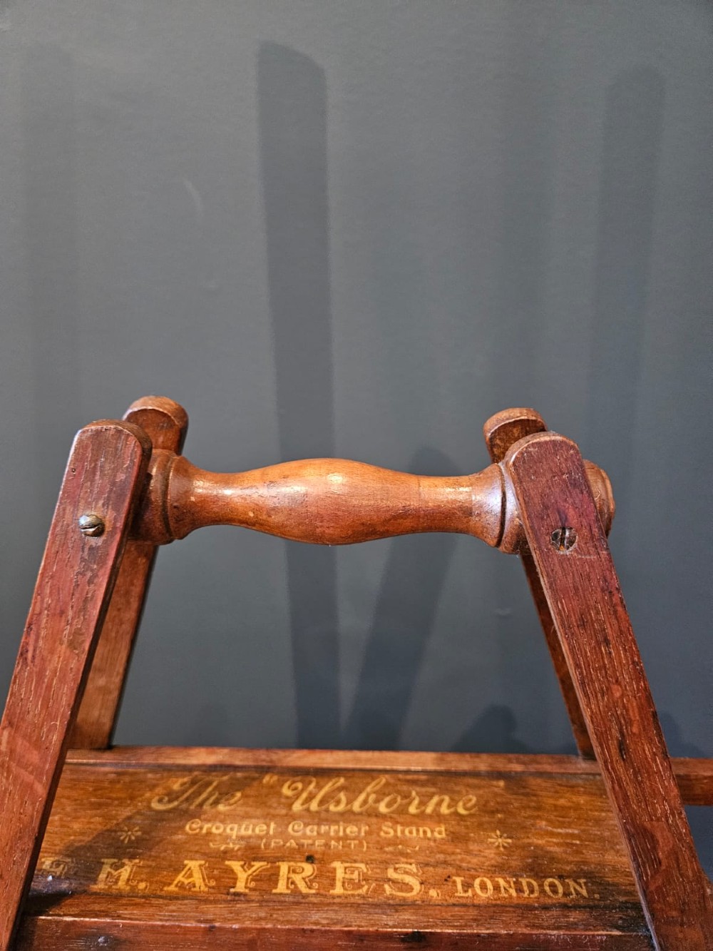 An Edwardian wooden croquet stand featuring four tall wooden mallets and painted croquet balls supported on a timber frame with a central turned carrying handle. View IV