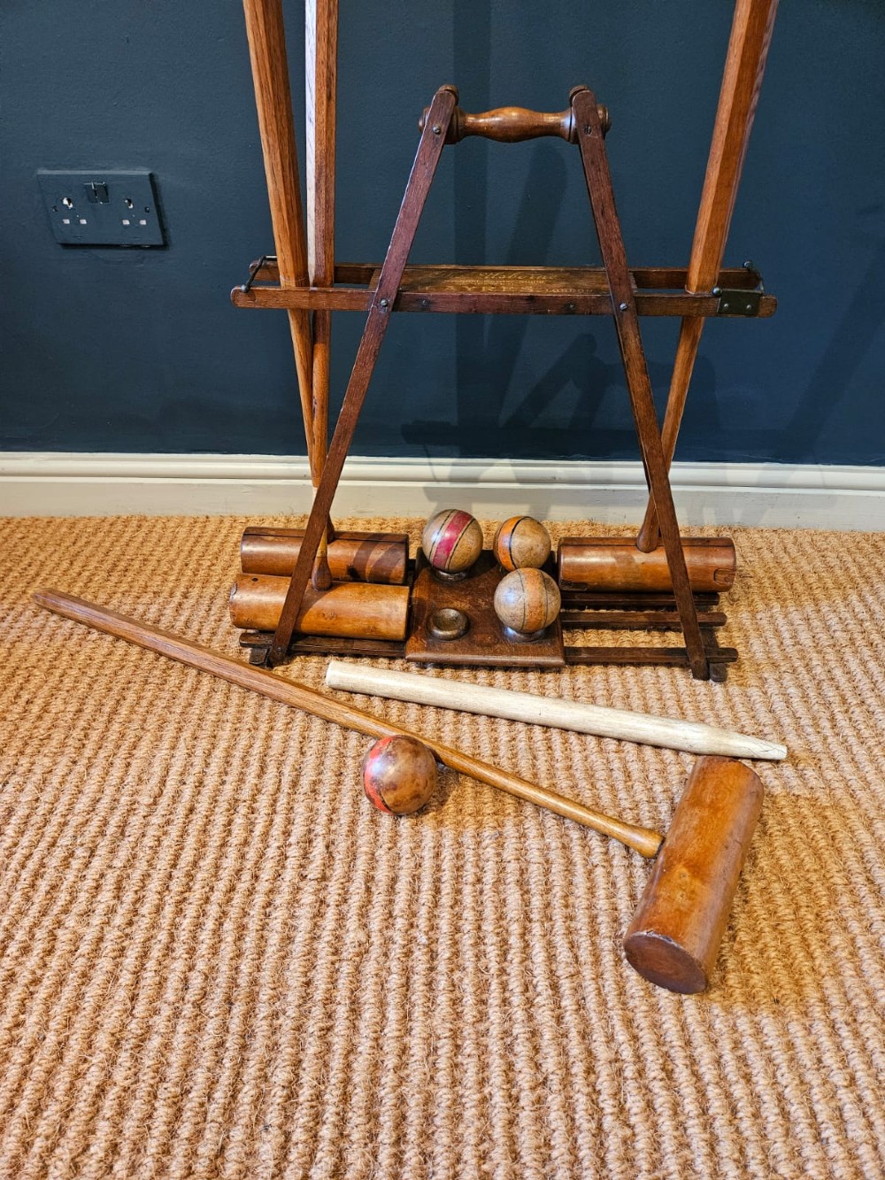 An Edwardian wooden croquet stand featuring four tall wooden mallets and painted croquet balls supported on a timber frame with a central turned carrying handle. View VIII