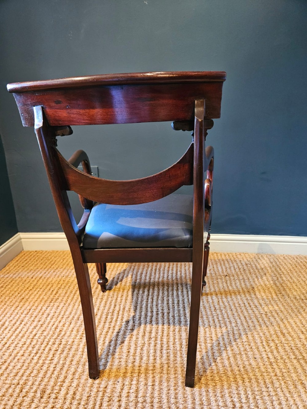 A 19th-century William IV dark mahogany desk chair featuring dynamic scroll arms, turned reeded front legs, and a black leather upholstered seat. View II