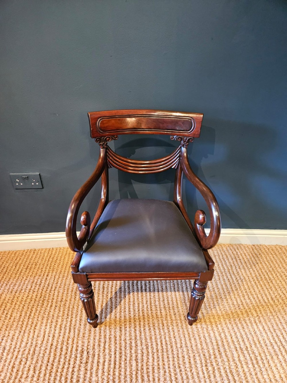 A 19th-century William IV dark mahogany desk chair featuring dynamic scroll arms, turned reeded front legs, and a black leather upholstered seat. View III