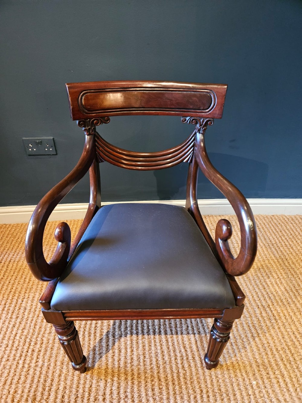 A 19th-century William IV dark mahogany desk chair featuring dynamic scroll arms, turned reeded front legs, and a black leather upholstered seat. View V