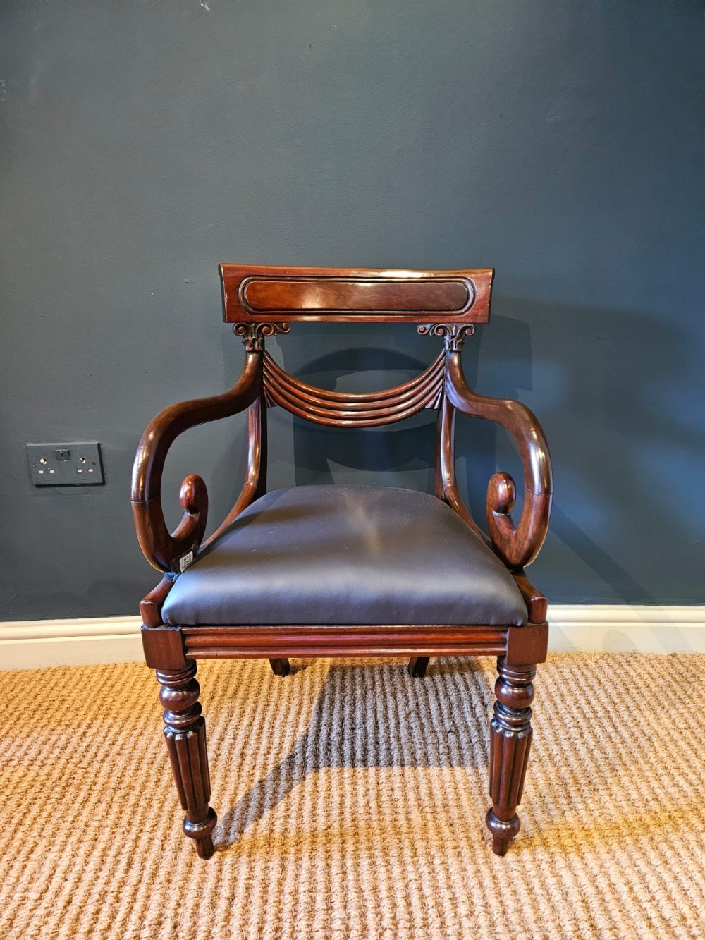 A 19th-century William IV dark mahogany desk chair featuring dynamic scroll arms, turned reeded front legs, and a black leather upholstered seat. View VII