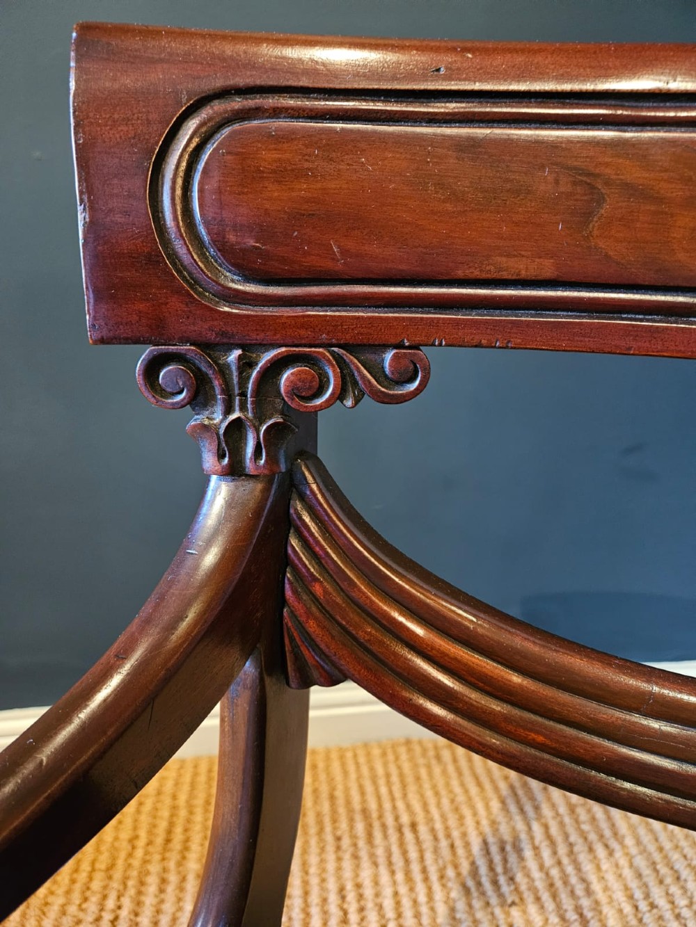 A 19th-century William IV dark mahogany desk chair featuring dynamic scroll arms, turned reeded front legs, and a black leather upholstered seat. View IX