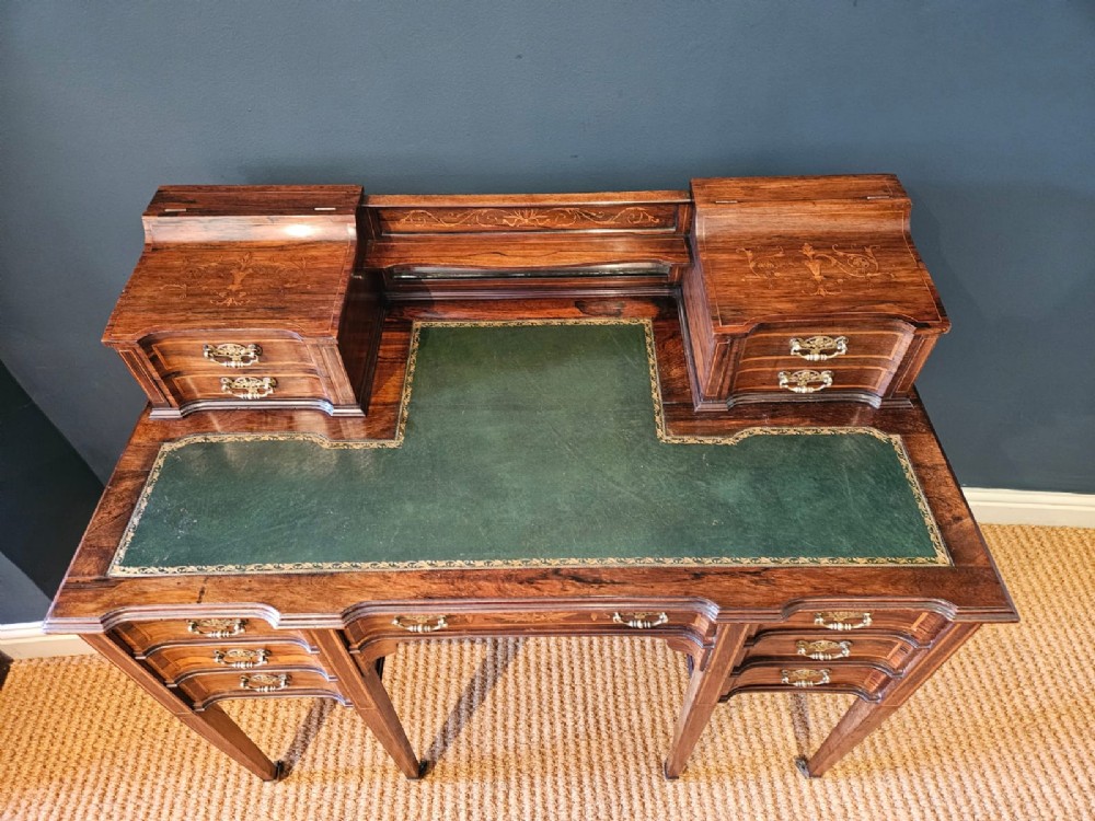 An Edwardian inlaid rosewood writing desk featuring a central green leather writing surface, raised side drawers, and tapered square legs. View II