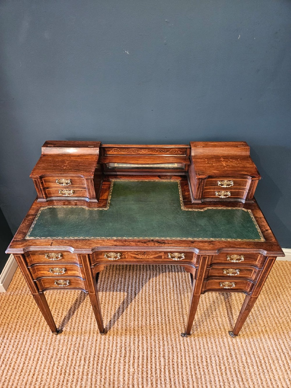 An Edwardian inlaid rosewood writing desk featuring a central green leather writing surface, raised side drawers, and tapered square legs. View VIII