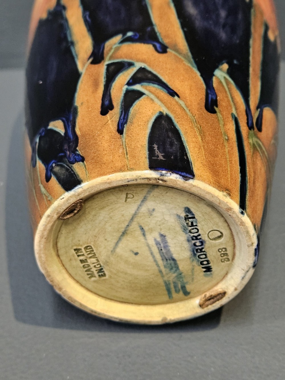 An Art Deco Moorcroft earthenware vase decorated with tube-lined orange poppy flowers on a deep cobalt blue background. View V