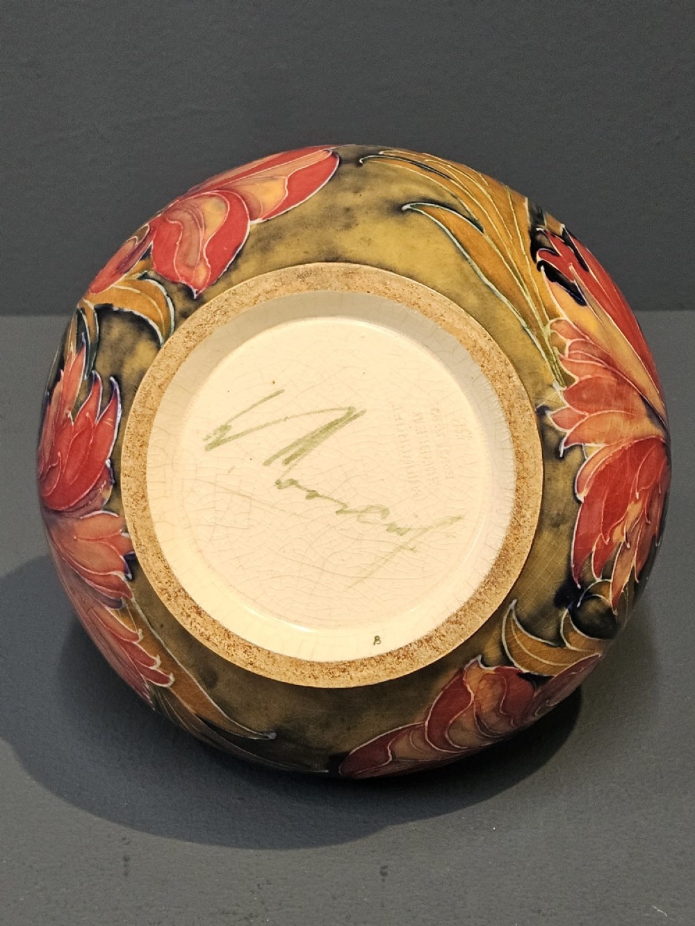 A squat ceramic vase decorated with Art Nouveau tube-lined floral motifs in ochre yellow, terracotta, and dark green glazes. View IV
