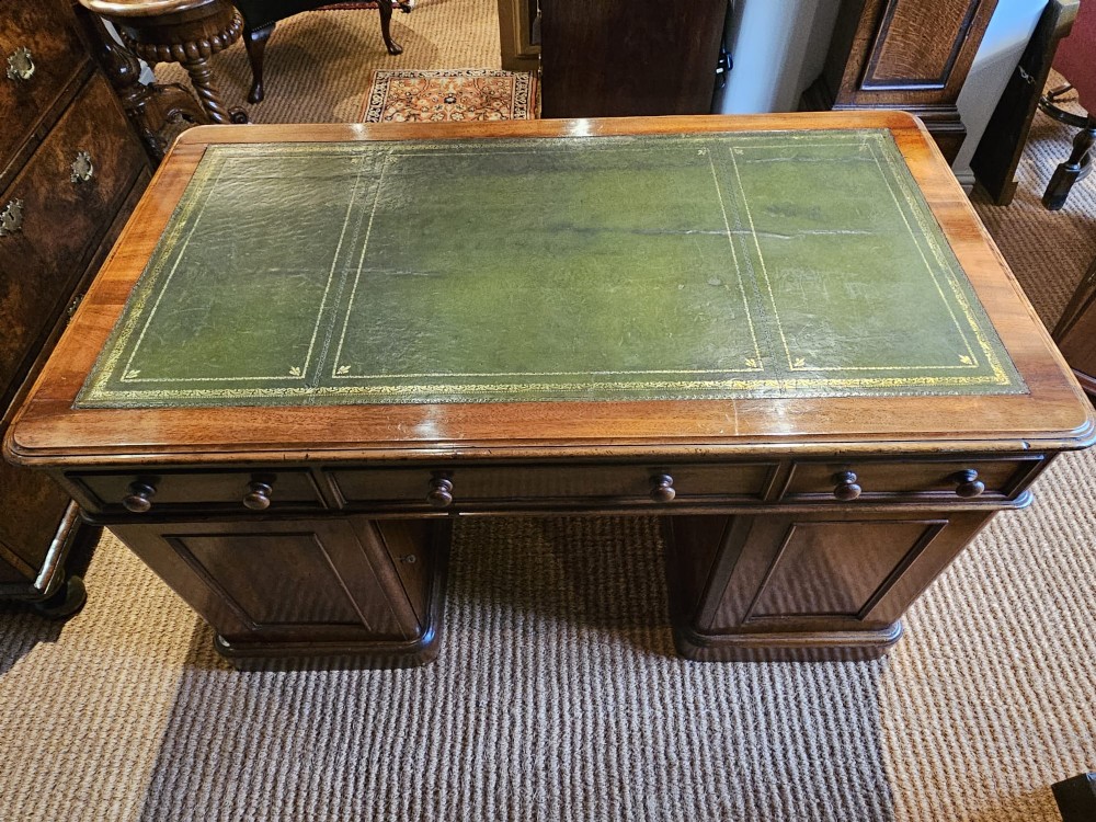 A Mid-Victorian mahogany partners desk featuring a pedestal layout with nine drawers on the front, turned timber knobs, and a solid plinth base. View V