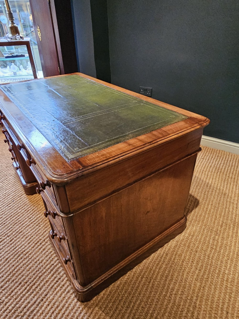 A Mid-Victorian mahogany partners desk featuring a pedestal layout with nine drawers on the front, turned timber knobs, and a solid plinth base. View VI