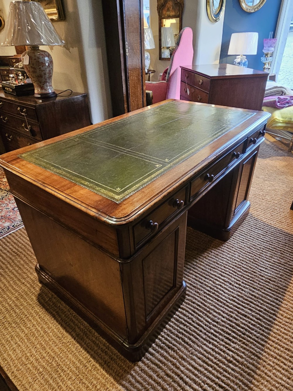 A Mid-Victorian mahogany partners desk featuring a pedestal layout with nine drawers on the front, turned timber knobs, and a solid plinth base. View IX
