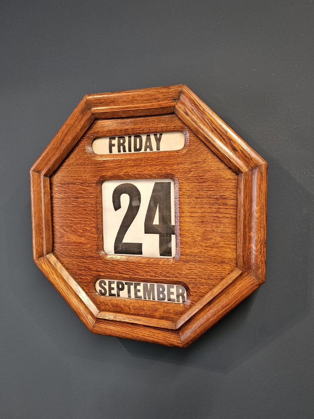 An octagonal Edwardian oak perpetual wall calendar with glazed apertures displaying the day, numerical date, and month on printed rollers. View II