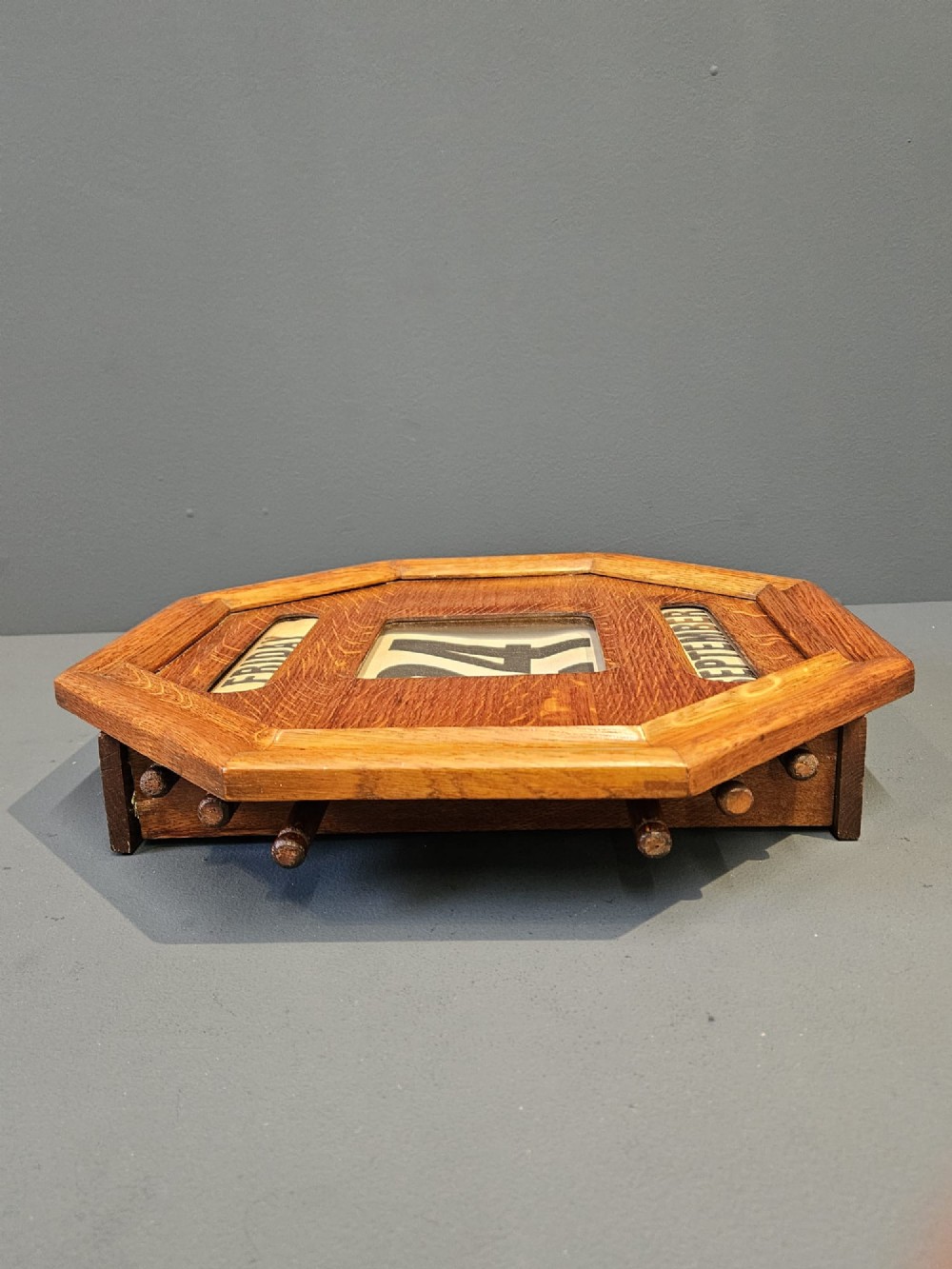 An octagonal Edwardian oak perpetual wall calendar with glazed apertures displaying the day, numerical date, and month on printed rollers. View V