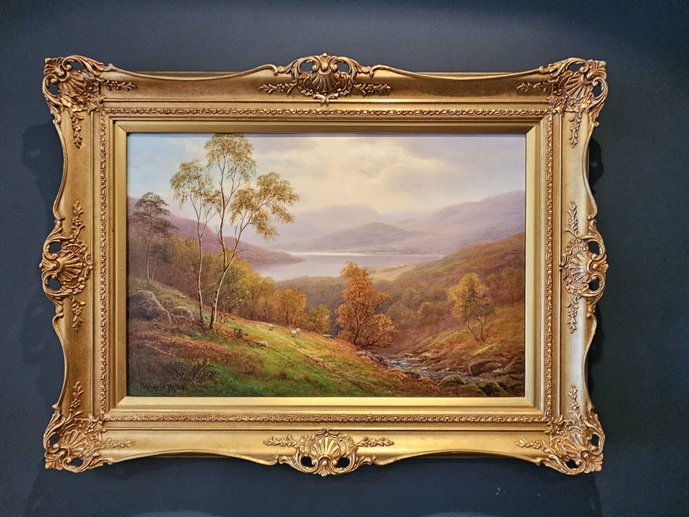 A Victorian landscape oil painting depicting a Lake District scene with hills and trees, enclosed in an ornate gold gilt frame.