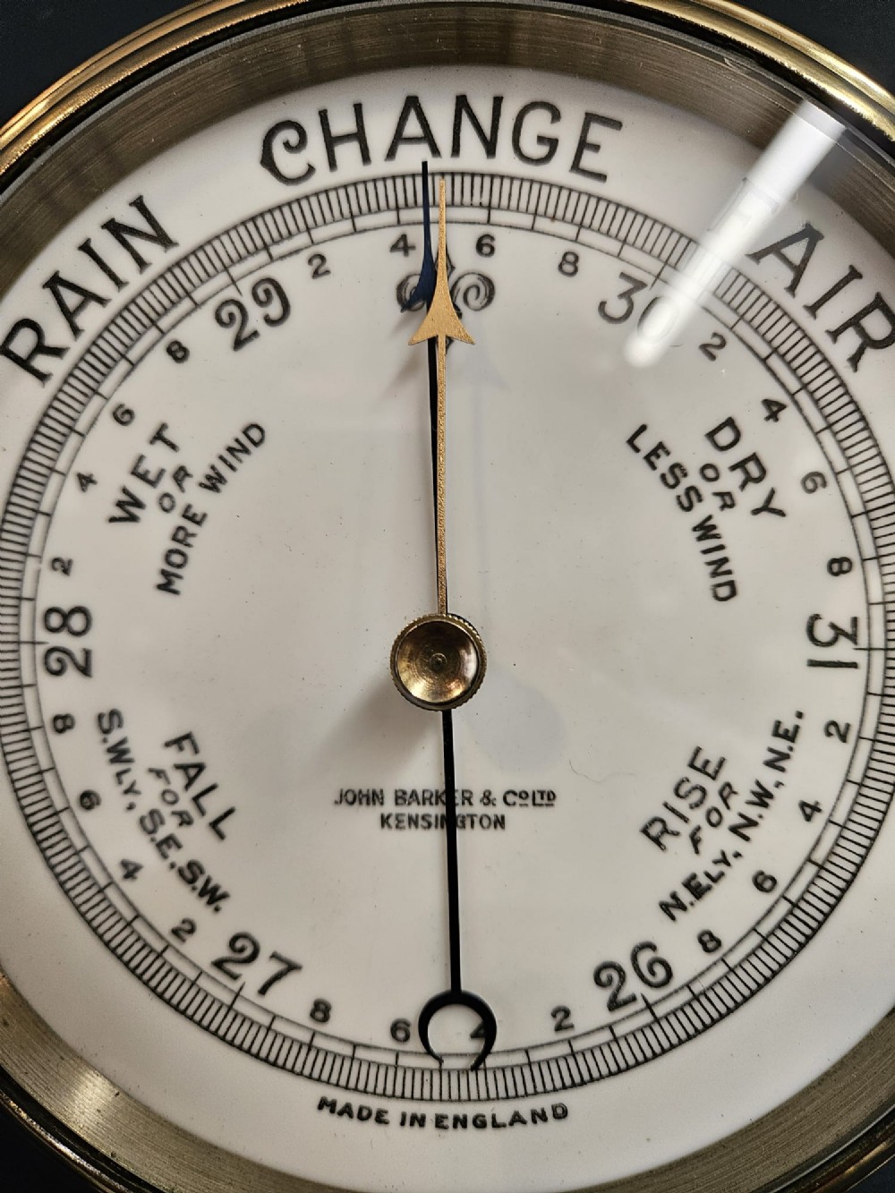 A circular Victorian brass bulkhead aneroid barometer with a cream dial mounted on a round wooden backplate. View IV