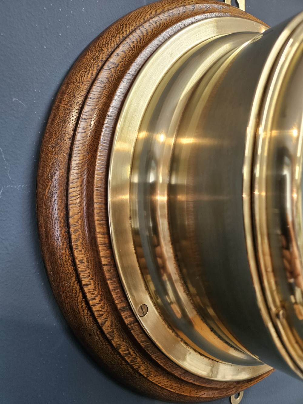 A circular Victorian brass bulkhead aneroid barometer with a cream dial mounted on a round wooden backplate. View VI