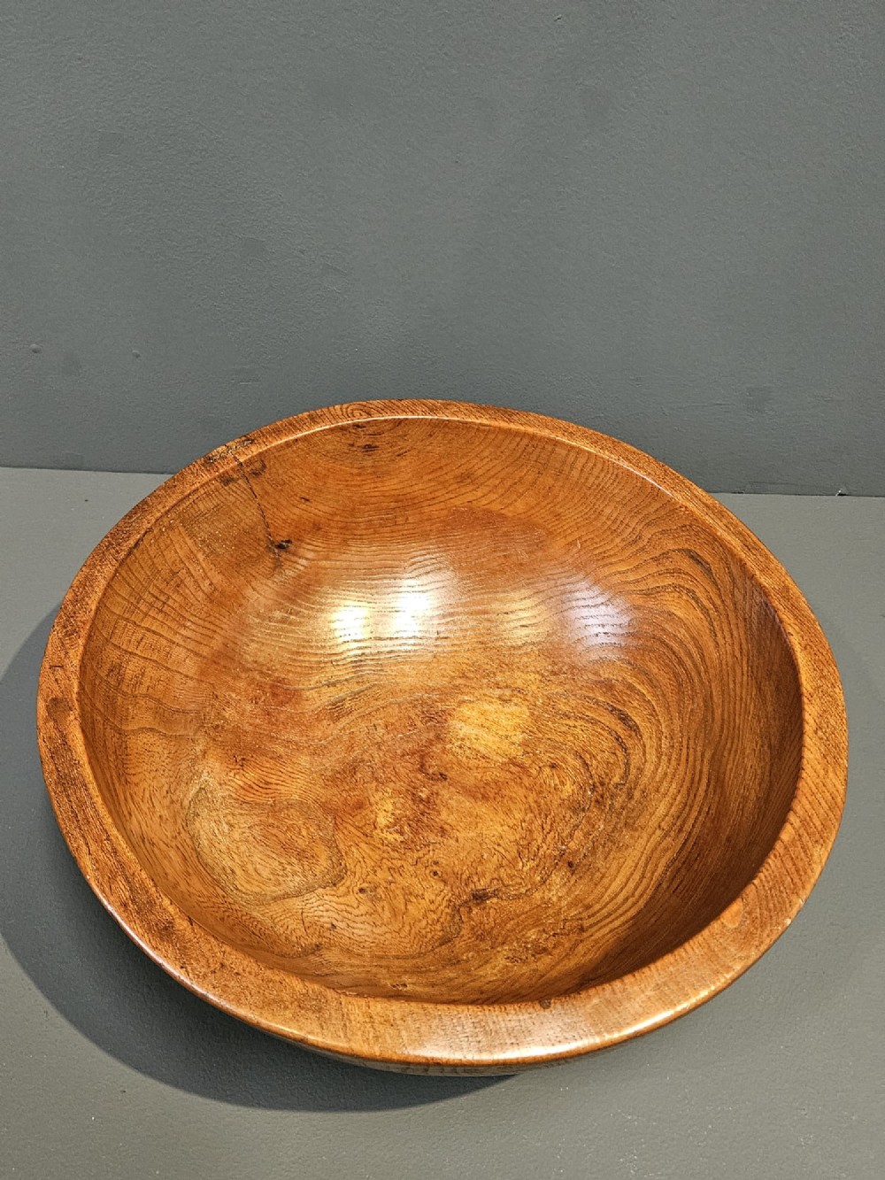 A turned early Victorian warm brown elm wood dairy bowl with a wide curved rim showing natural wood grain. View IV
