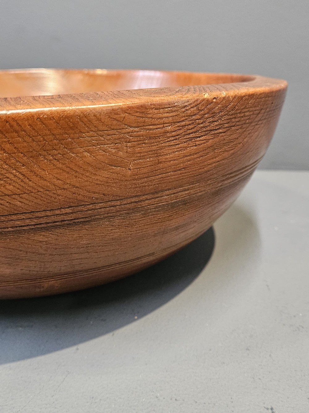 A turned early Victorian warm brown elm wood dairy bowl with a wide curved rim showing natural wood grain. View V