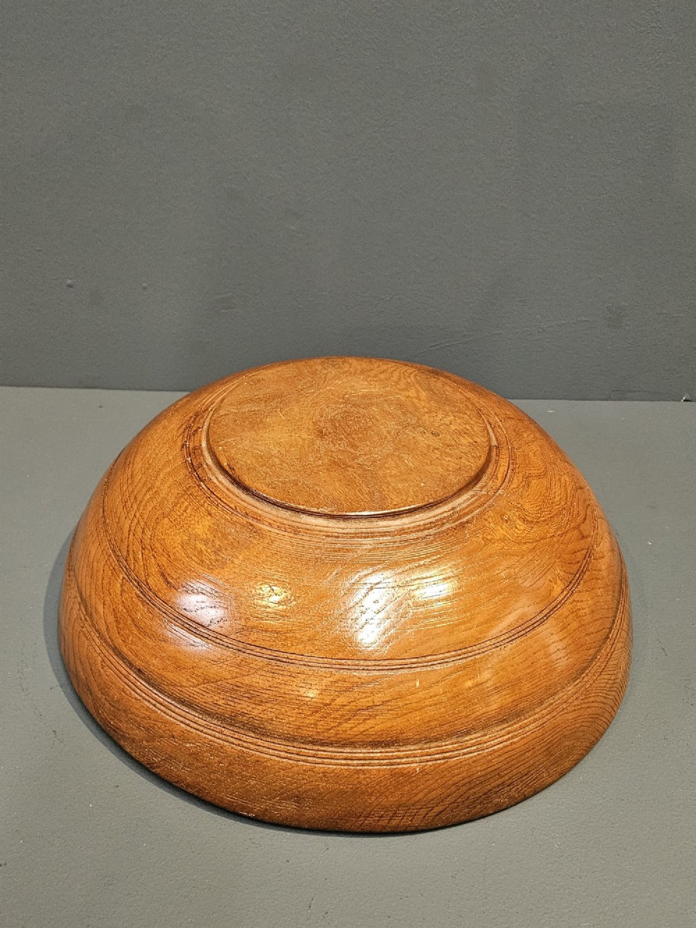 A turned early Victorian warm brown elm wood dairy bowl with a wide curved rim showing natural wood grain. View VII