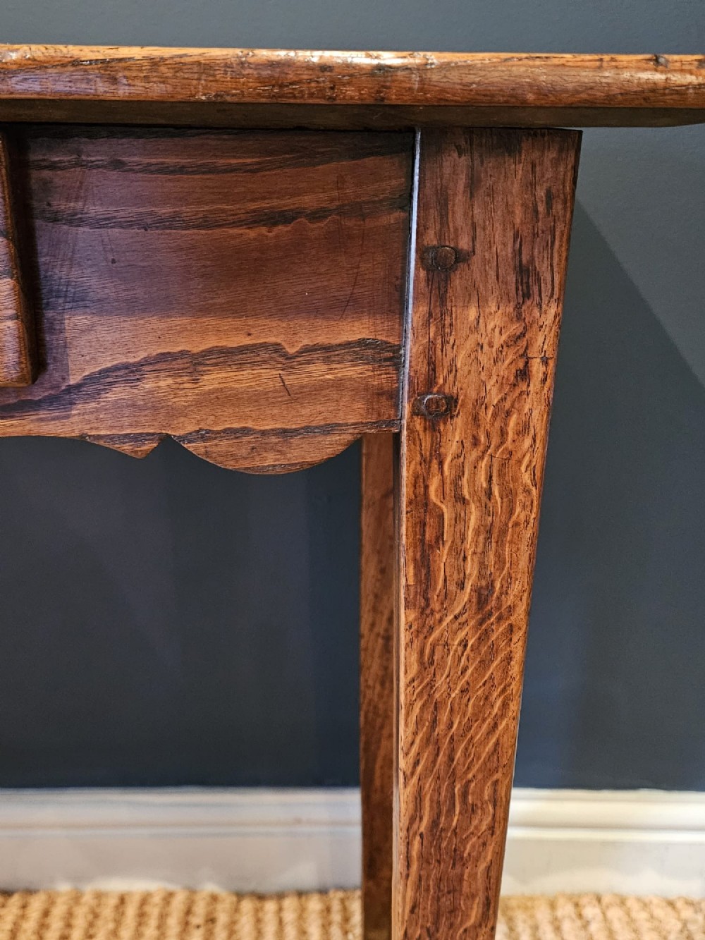 A George III elm single drawer side table featuring a rectangular top, a shaped apron, a turned wooden drawer knob, and tapered square legs. View III
