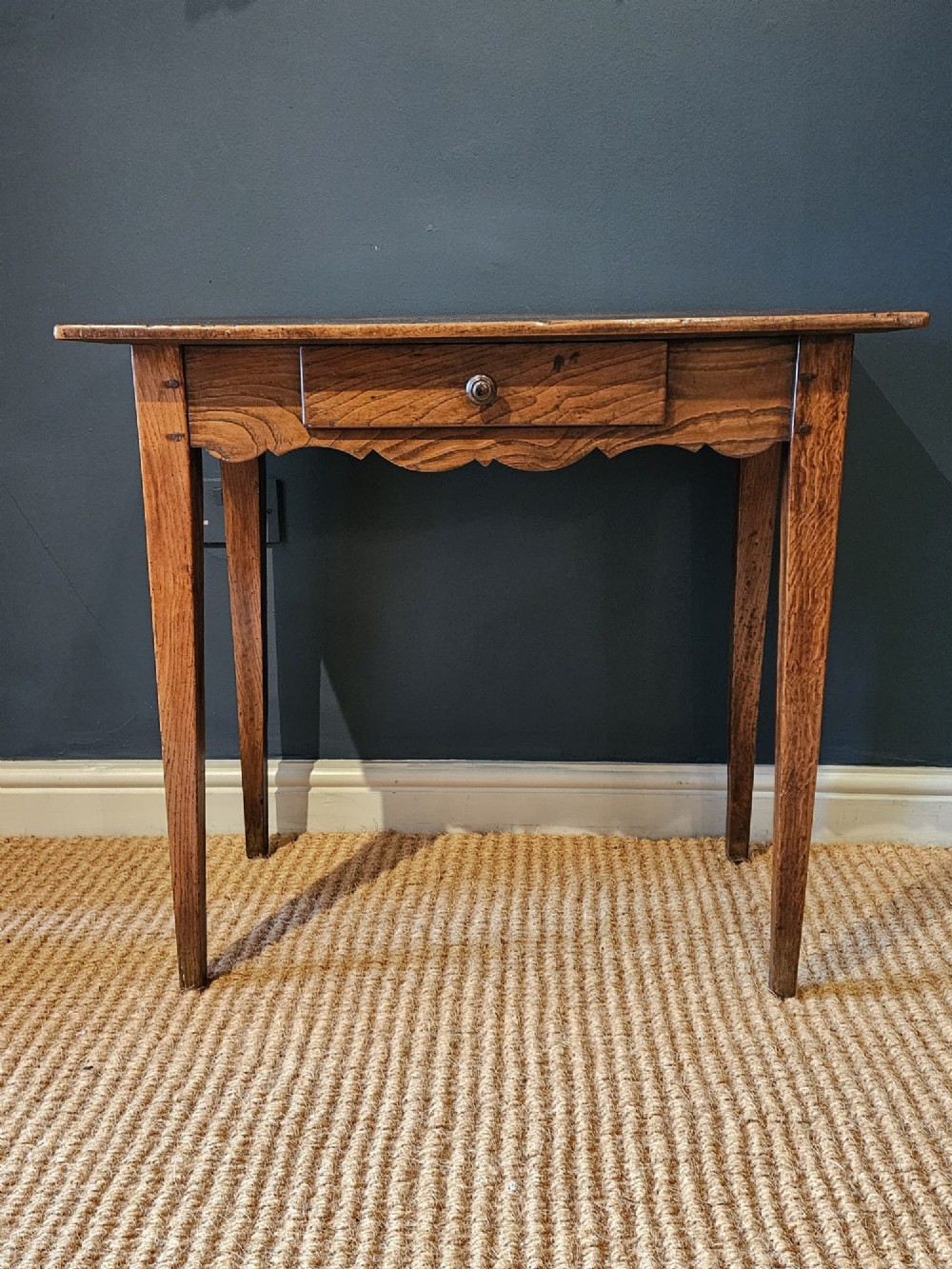 A George III elm single drawer side table featuring a rectangular top, a shaped apron, a turned wooden drawer knob, and tapered square legs. View IV