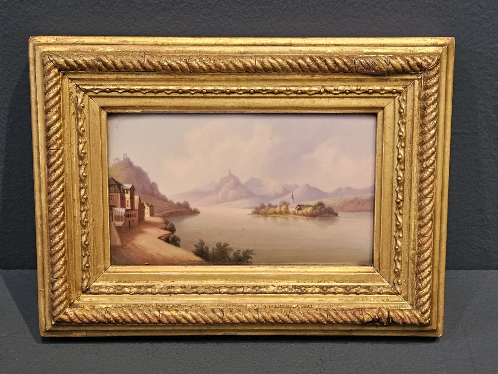A pair of rectangular Victorian hand-painted porcelain plaques depicting European landscape scenes set within ornate giltwood rope-twist frames. View II