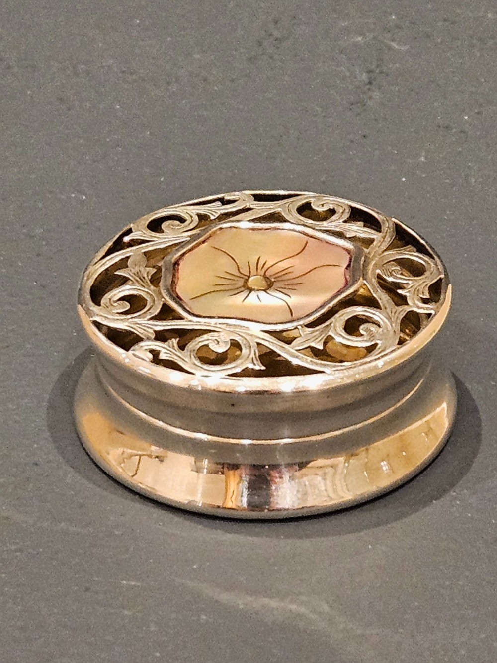 A circular Edwardian silver pot-pourri box featuring a pierced scrollwork lid set with a central mother-of-pearl floral inset.