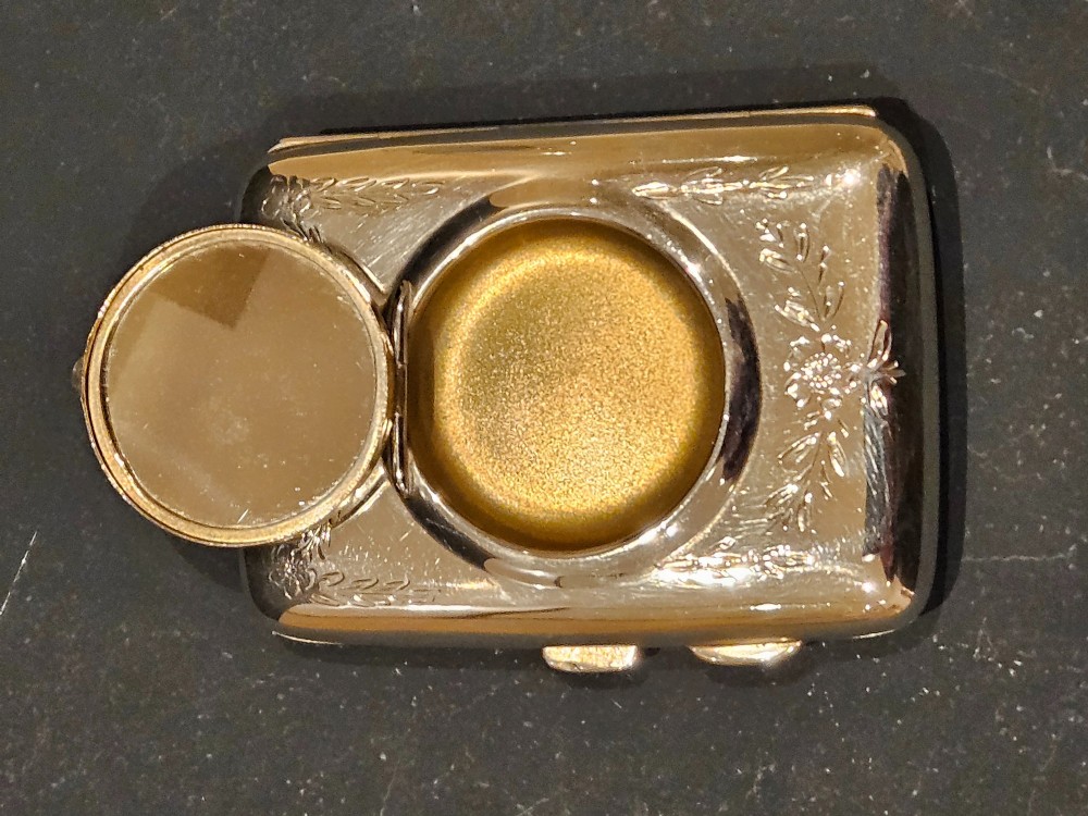 A rectangular engraved sterling silver cheroot case featuring floral motifs and an integrated circular hinged compact lid. View III