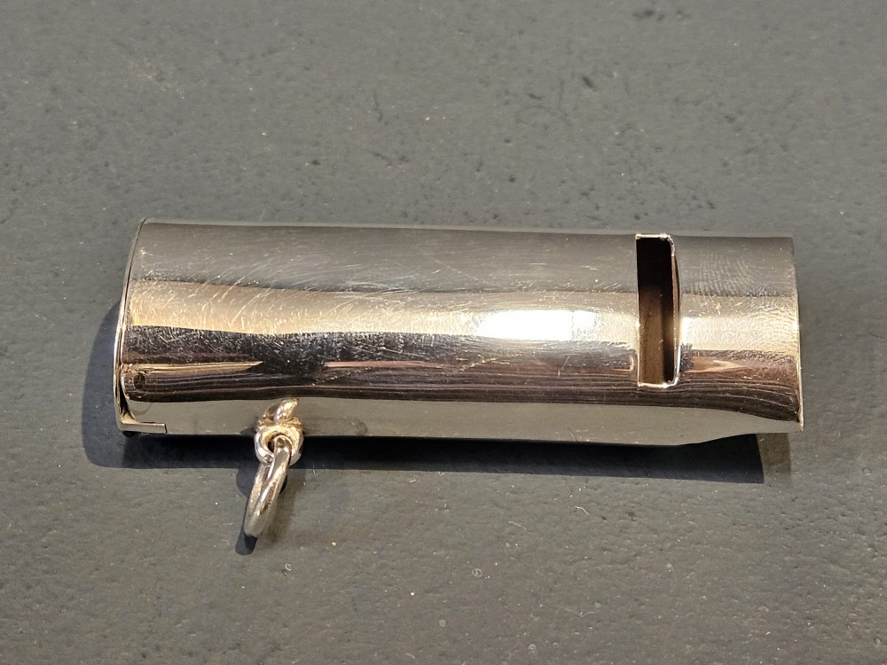 A polished Victorian sterling silver combined vesta case and whistle standing upright with a small suspension ring attached at the base. View II