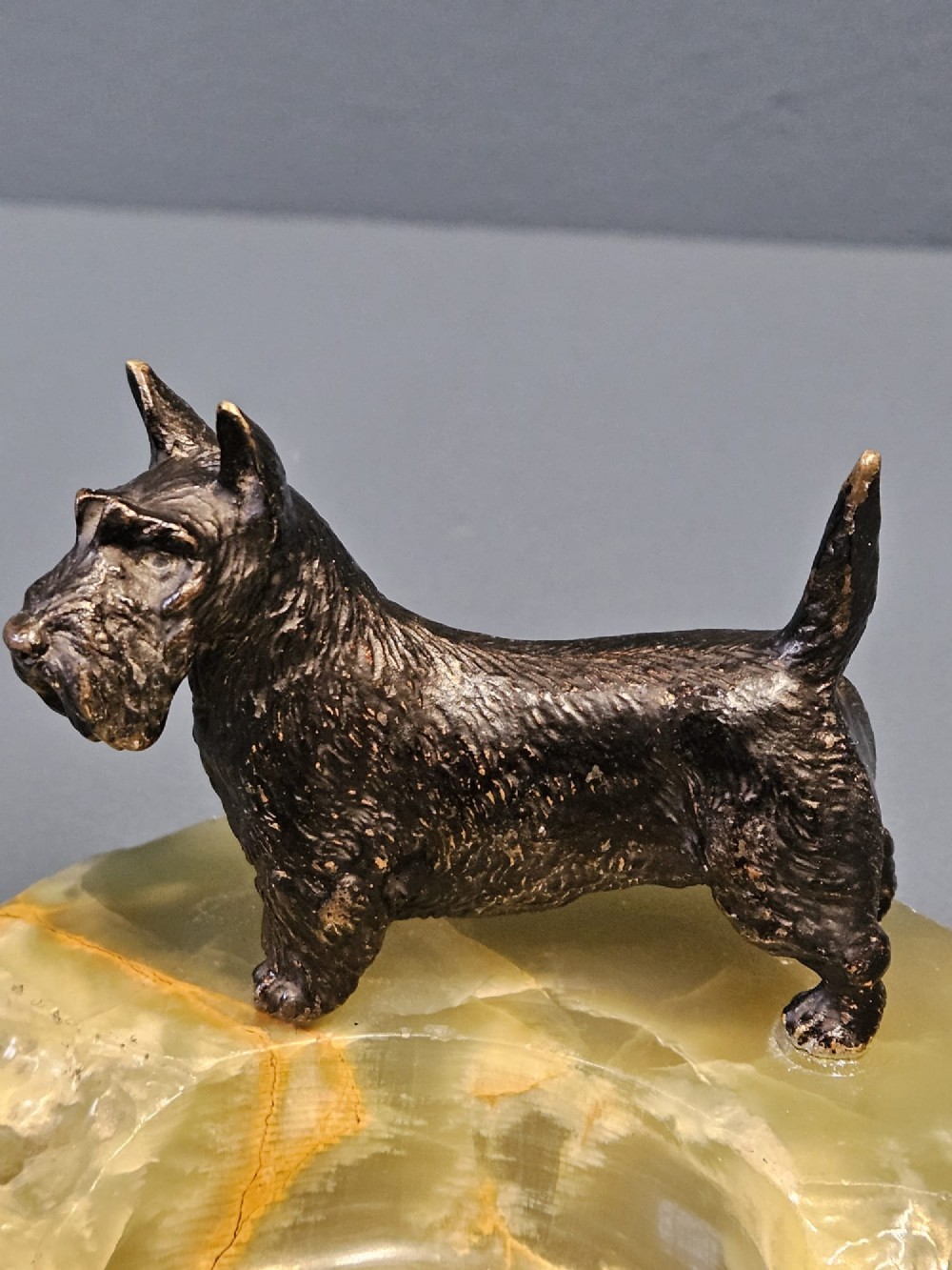 A cold painted bronze Scottish Terrier figure standing on a carved pale green onyx dish with natural veining. View II