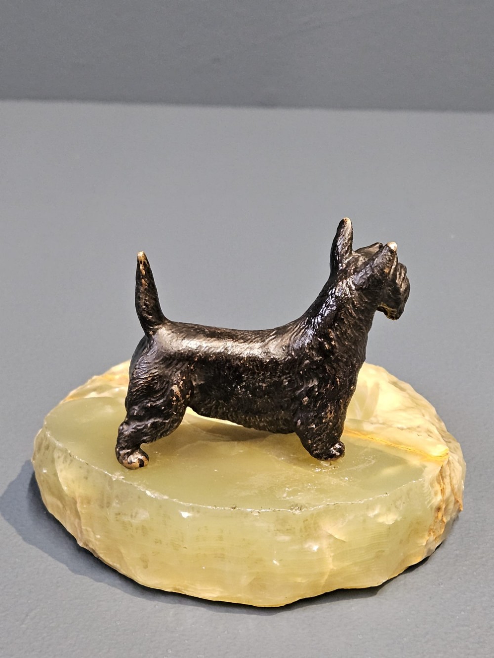 A cold painted bronze Scottish Terrier figure standing on a carved pale green onyx dish with natural veining. View V