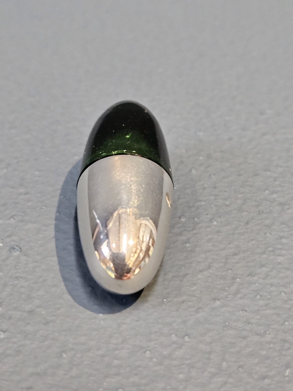 A Victorian torpedo-shaped scent bottle featuring a polished silver top half and a deep emerald green glass base. View II