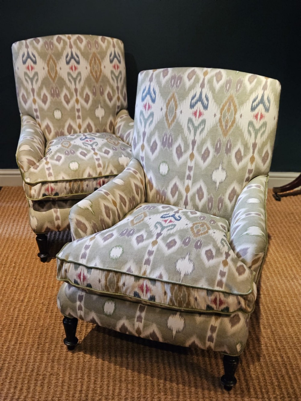 A pair of Victorian armchairs reupholstered in a geometric sage green ikat linen fabric with turned dark timber front legs.