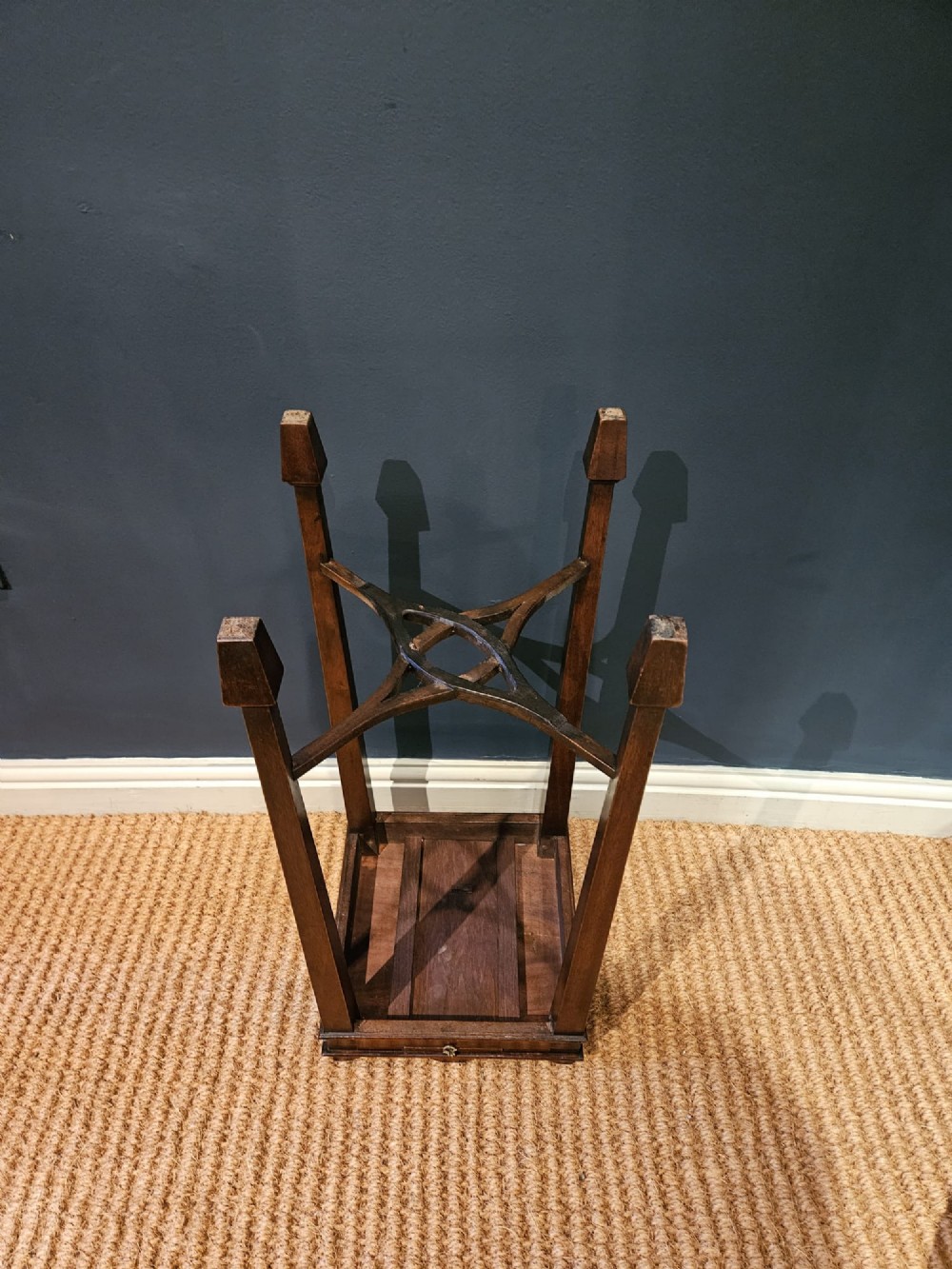 A tall Edwardian mahogany kettle stand featuring a scalloped gallery top, a small drawer with a brass pull, square tapered legs, and a crossed stretcher base. View V