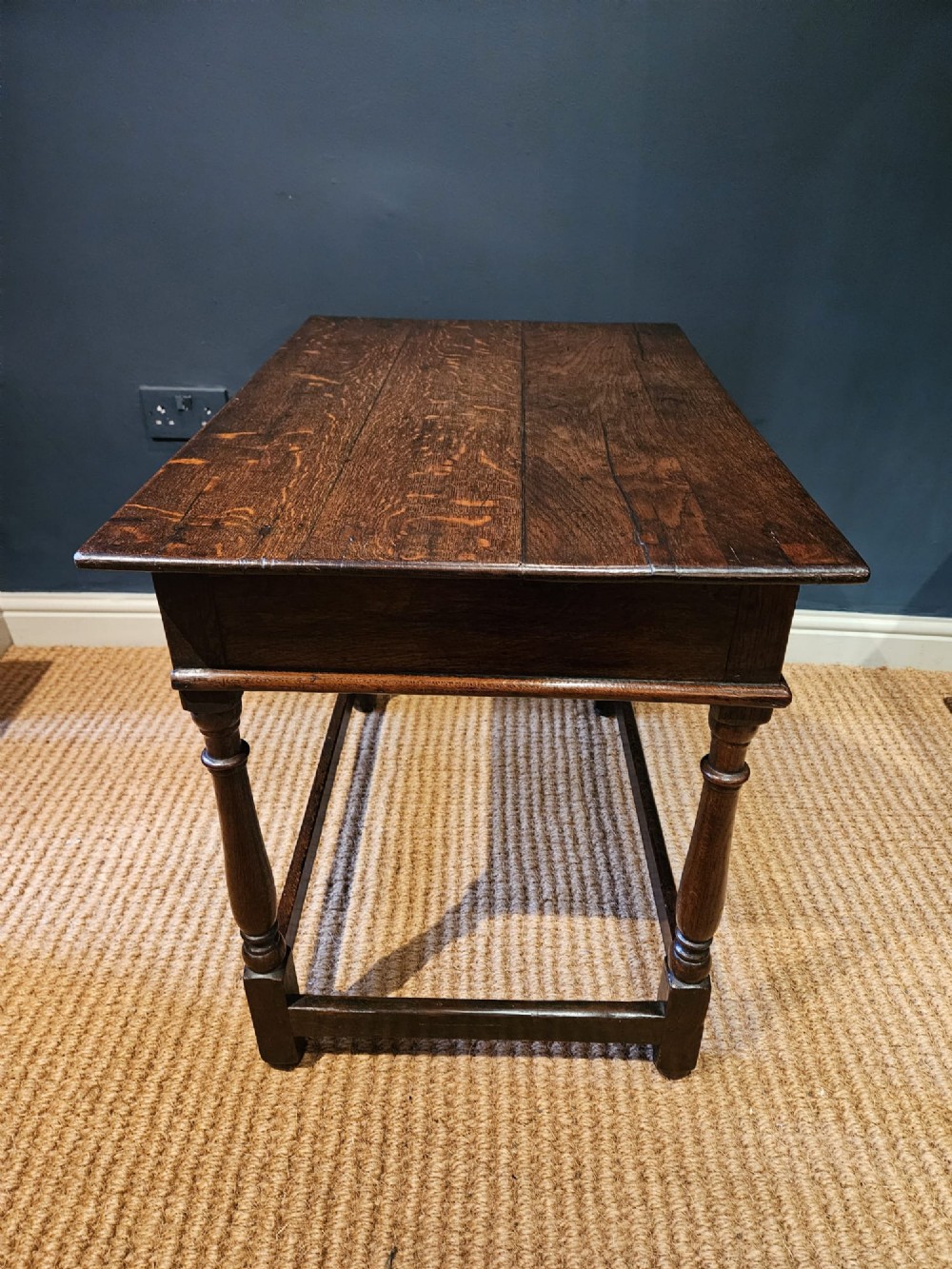A dark oak George I side table featuring a single frieze drawer with brass drop handles and turned legs joined by stretchers. View III