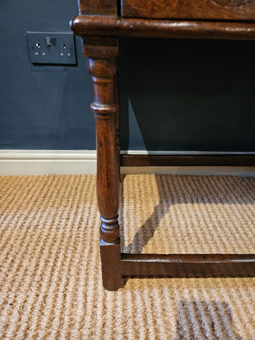 A dark oak George I side table featuring a single frieze drawer with brass drop handles and turned legs joined by stretchers. View VII