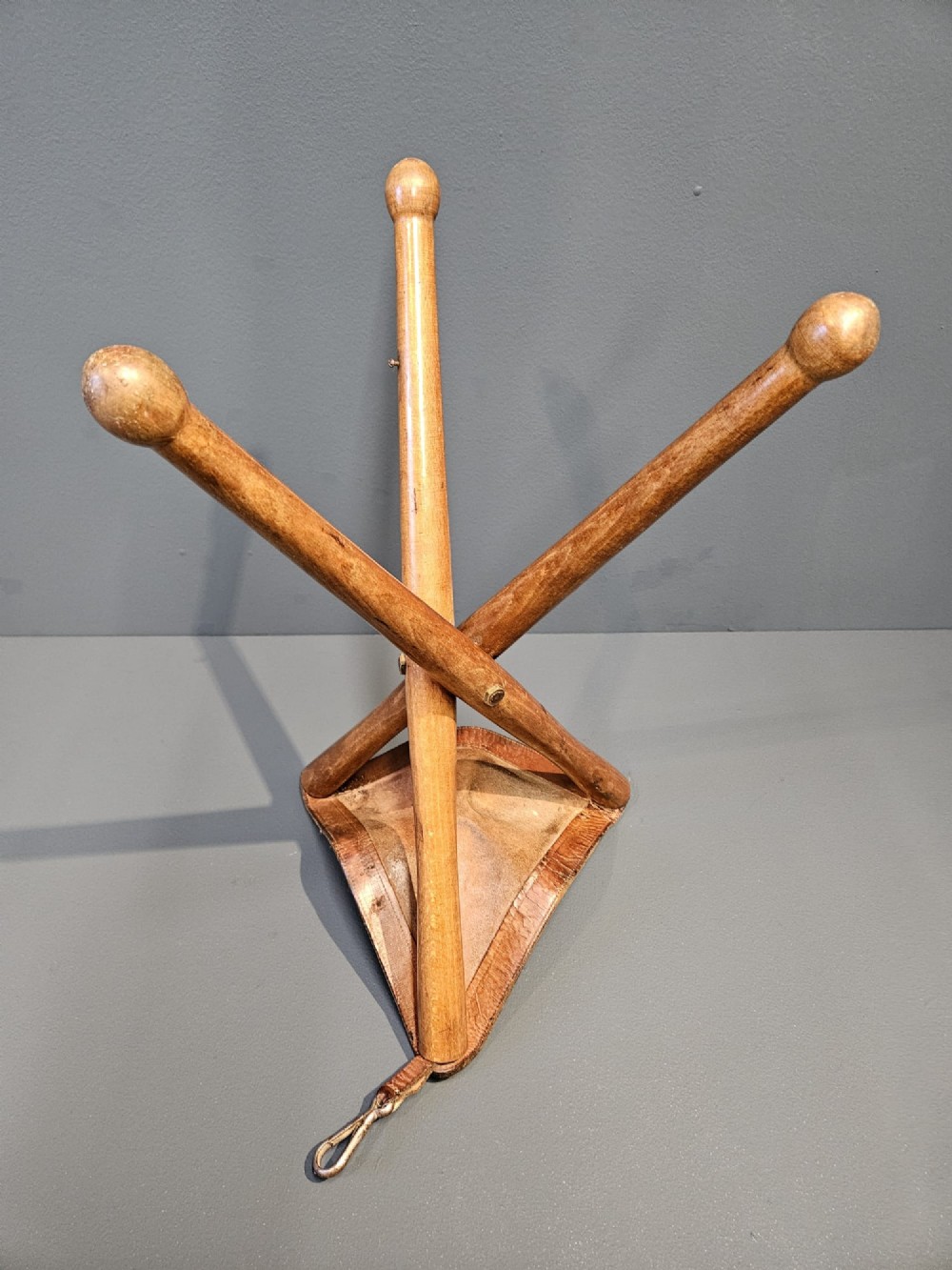 An Arts and Crafts period folding tripod campaign stool with three turned wooden legs and a stitched tan leather seat. View VII