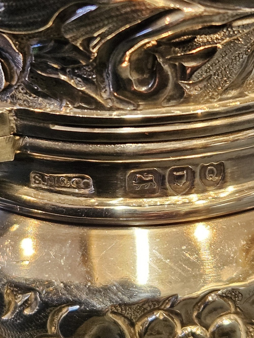 A cylindrical Victorian sterling silver cologne bottle with detailed chased floral scrollwork, bird motifs, and a matching screw cap. View III